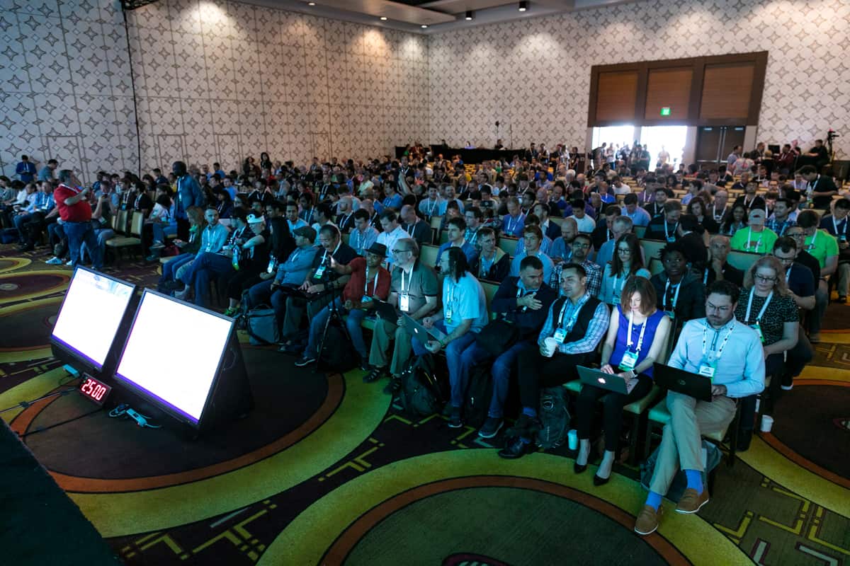 A large number of event attendees in the event hall getting seated for a seminar