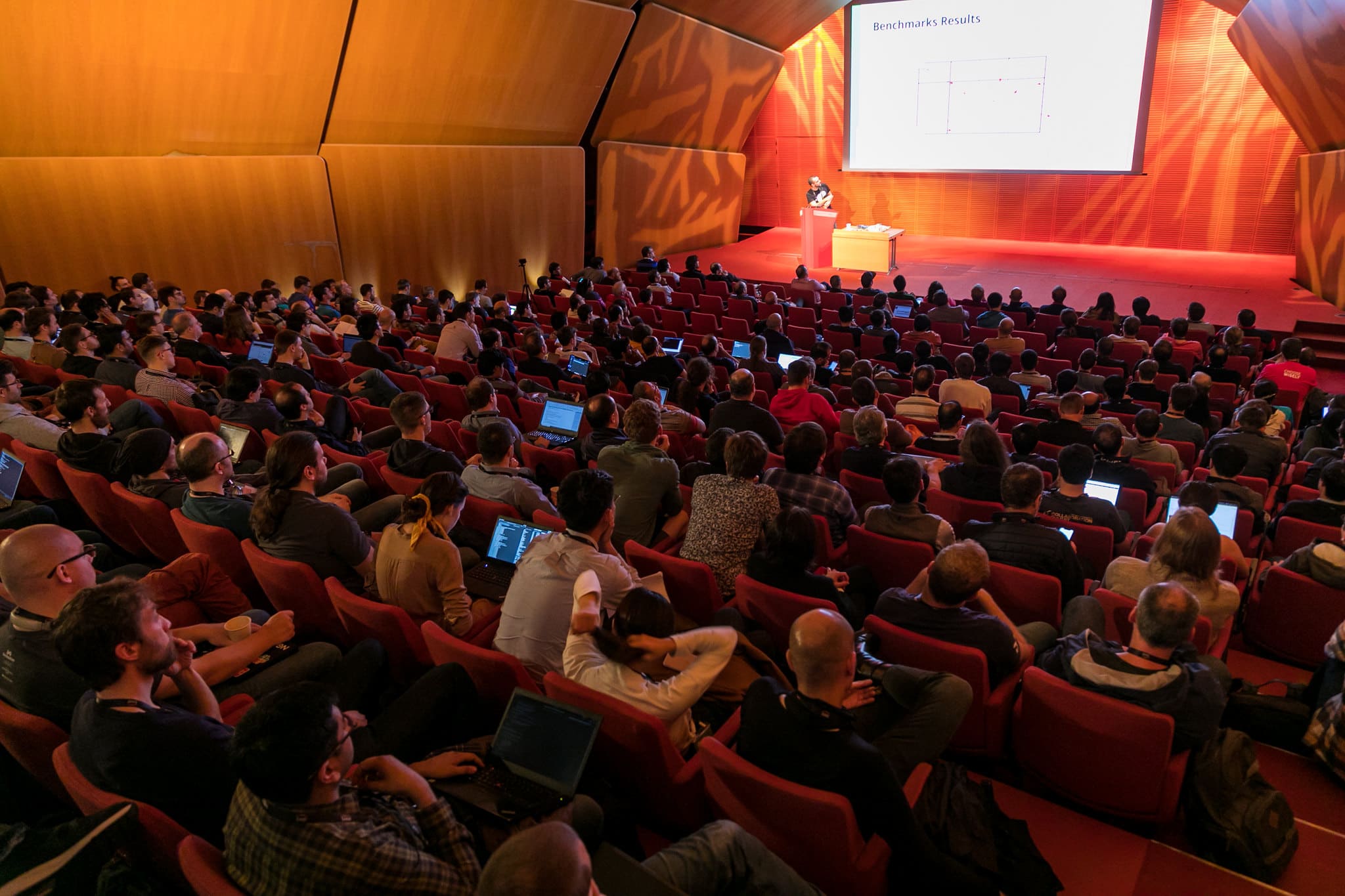 Attendees sitting in an auditorium with their laptops listening to the speaker during a seminar