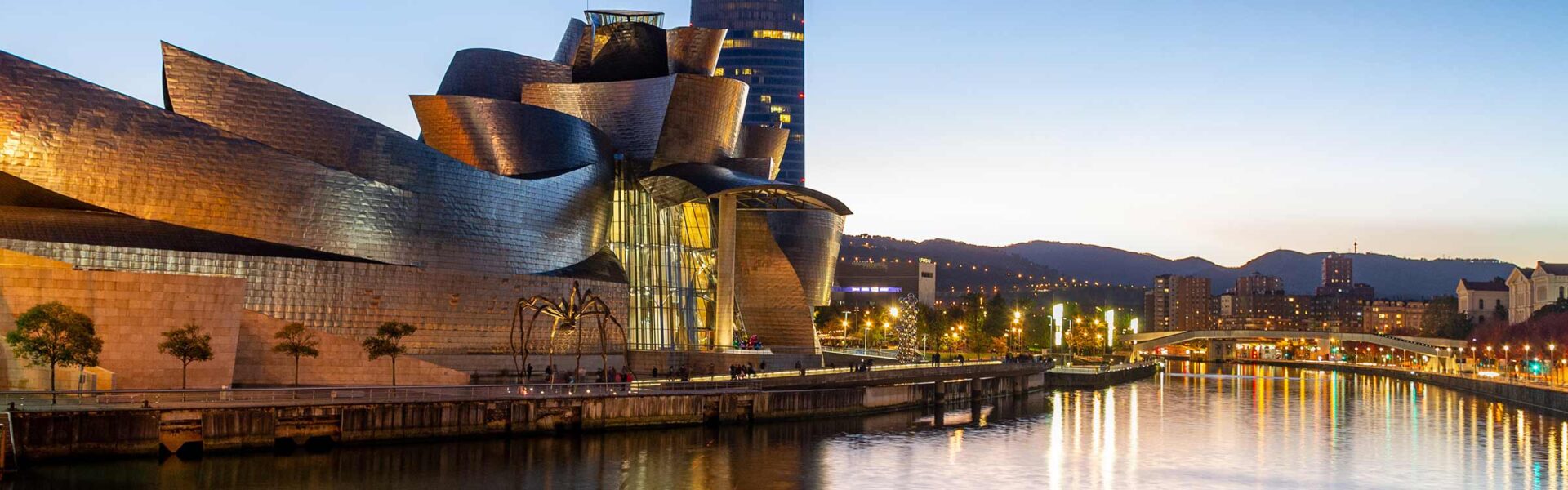 View in the evening along the river in Bilbao Spain, with the Guggenheim Museum featured.