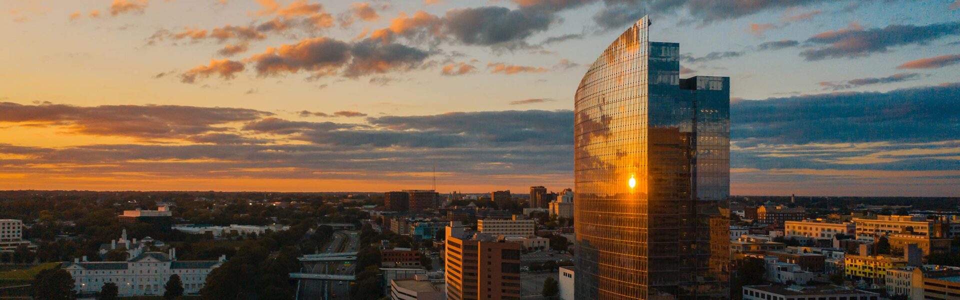 Overhead view of the city of Richmond, VA with the sunset reflecting off of a glass skyscraper.