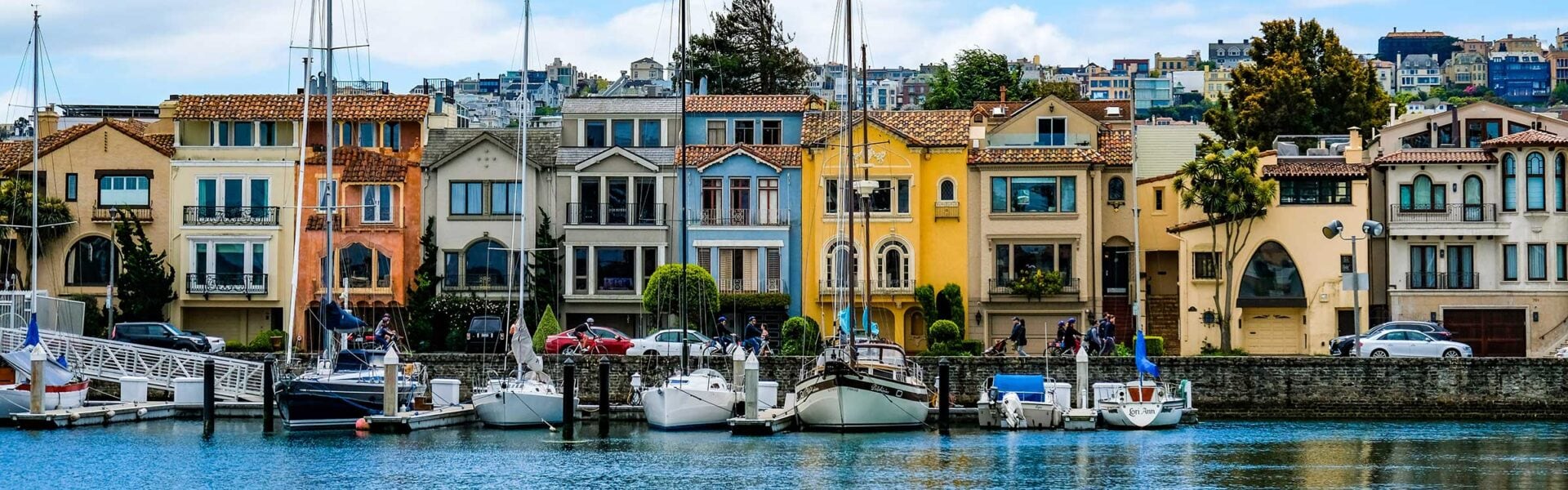 San Francisco shoreline at the harbor, with colorful houses & boats in the water.