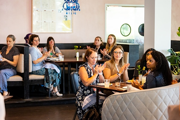 Women & non-binary attendees gathered for a lunch, clapping.