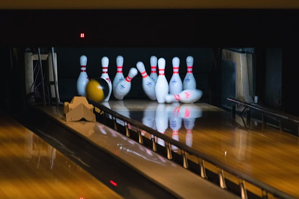 A bowling ball knocking down pins.