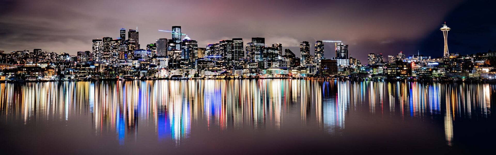 Seattle at night with the lights reflecting off of the water.
