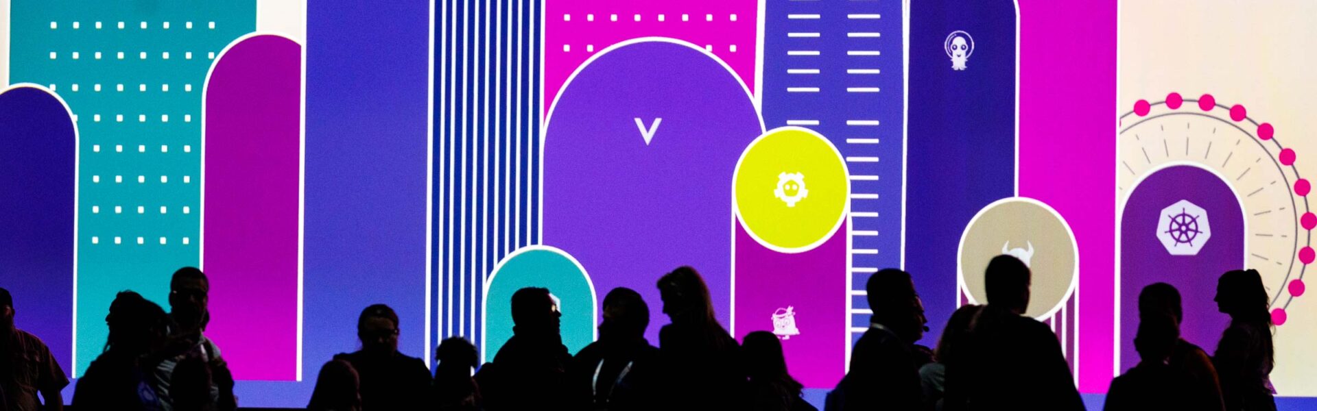 Silhouettes of a crowd moving to their seats in front of a colorful backdrop.