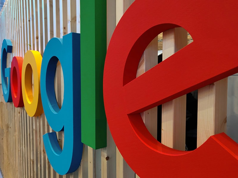 The Google sign hanging on a wood fence.