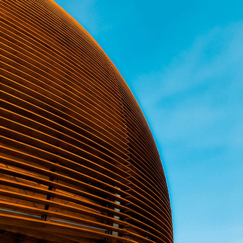 Round, brown building with a blue sky behind it.