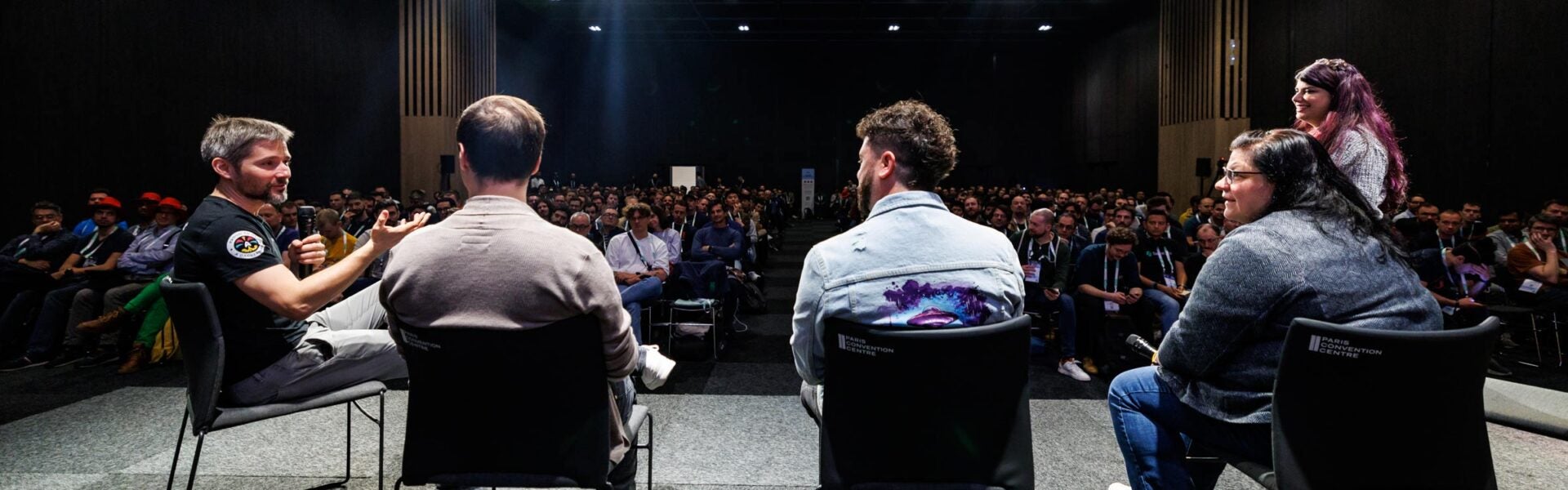 A group of speakers sitting on stage talking to one another at an event.