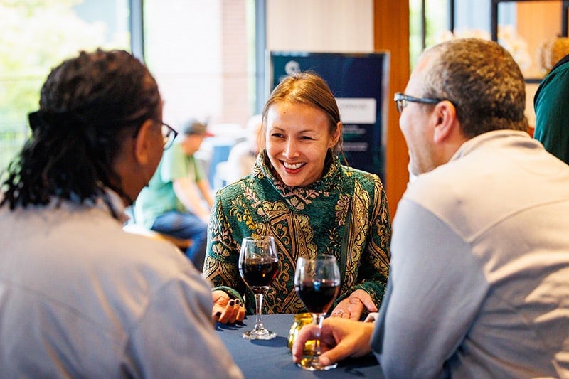 Three event attendees having a conversation while seated at a table.