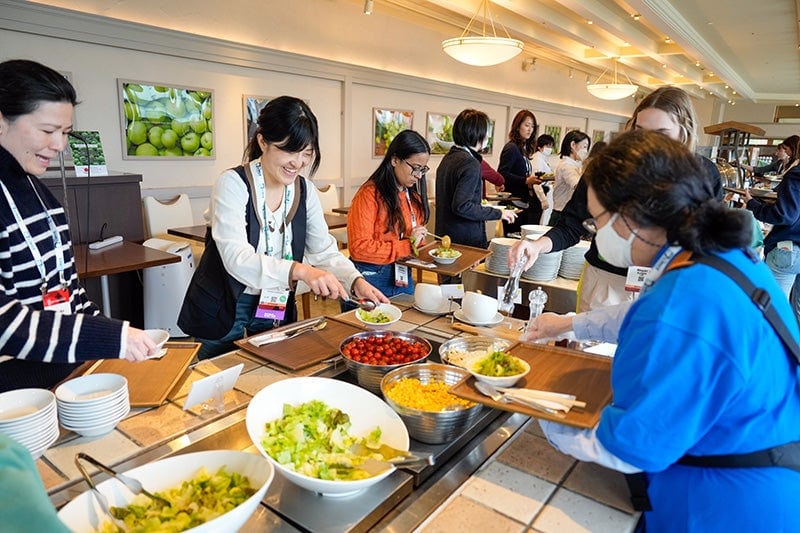 A group of women getting food from a buffet.