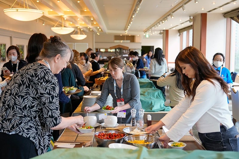 A group of women getting food from a buffet.