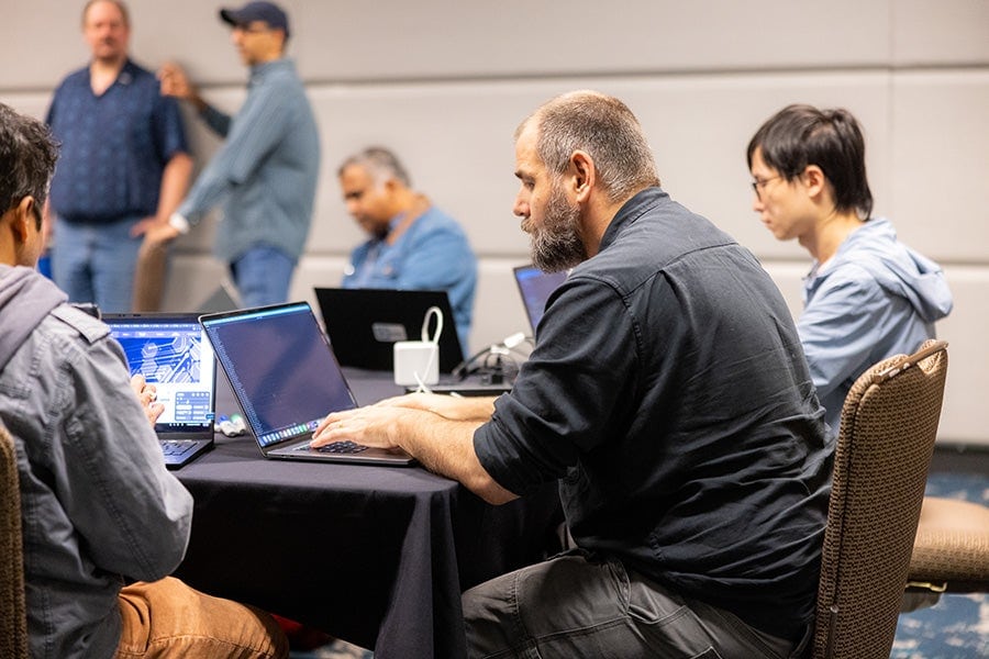 A group of people sitting around a table working on their laptops.