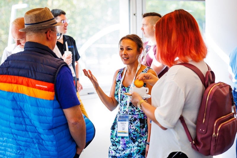 A group of attendees gathered in a circle enjoying refreshments and talking.