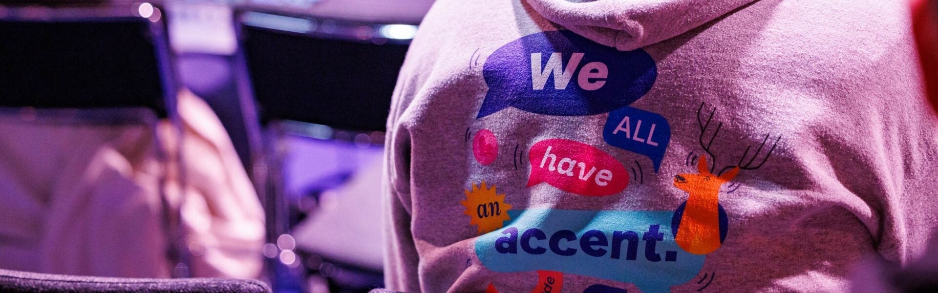 The back of a sweatshirt that says "We all have an accent."