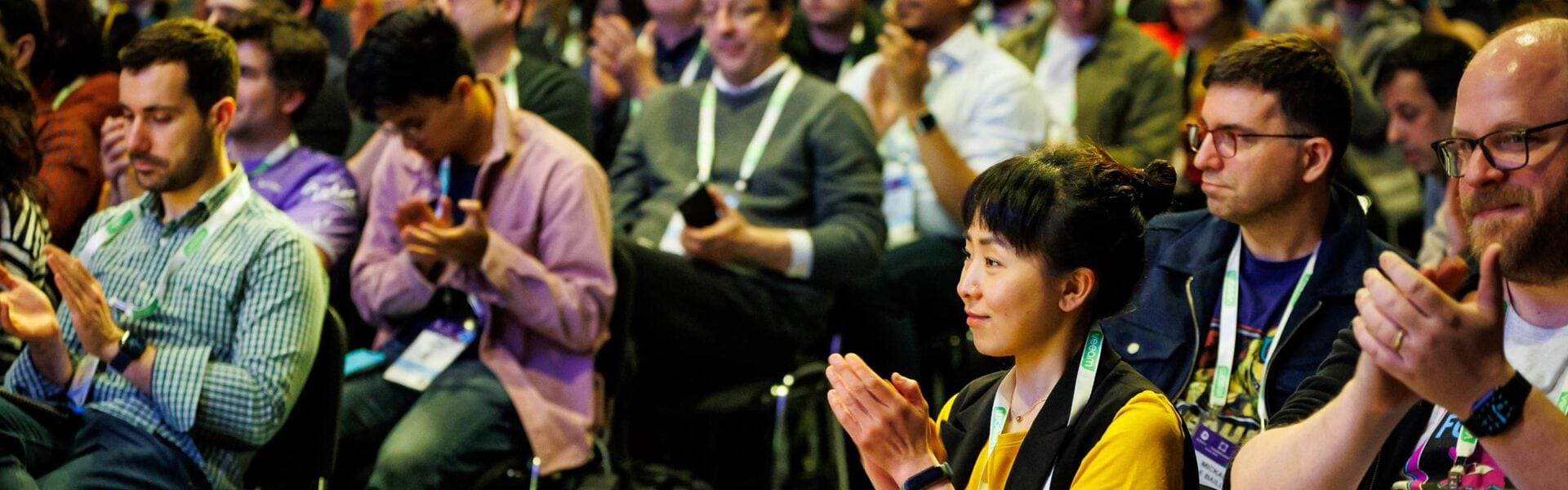 A crowd of seated attendees smiling and clapping.