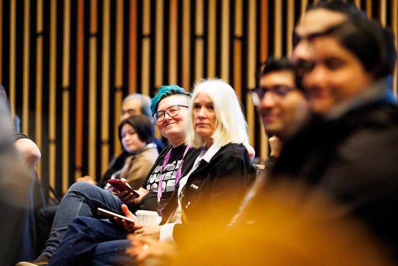 Smiling attendees seated in a row during a session.