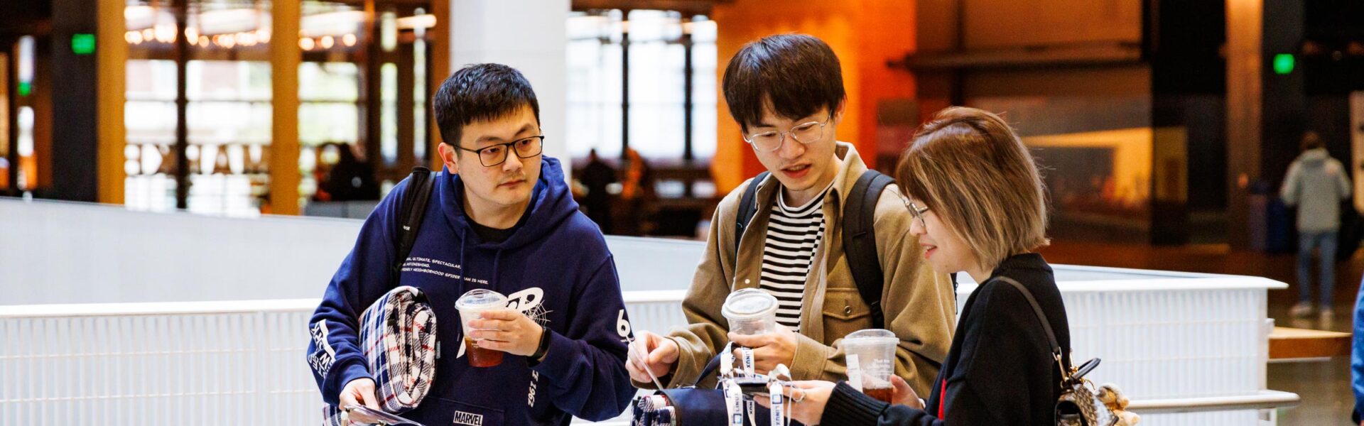 A group of 3 attendees looking at their event badges.