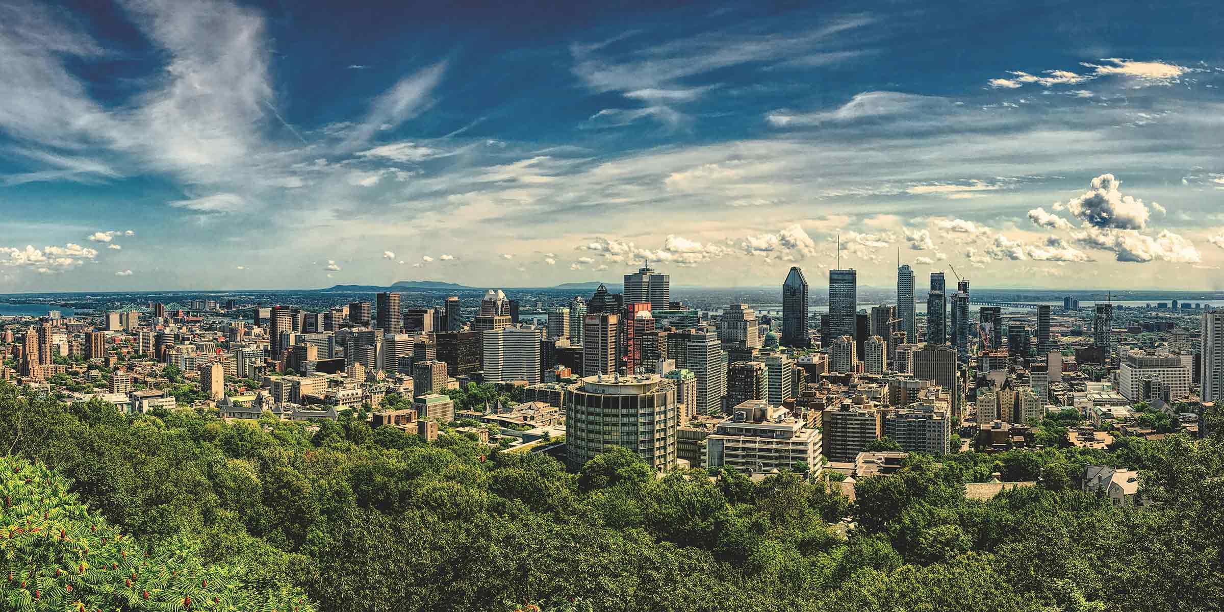 A panoramic view of the city of Montreal with blue skies and white clouds.