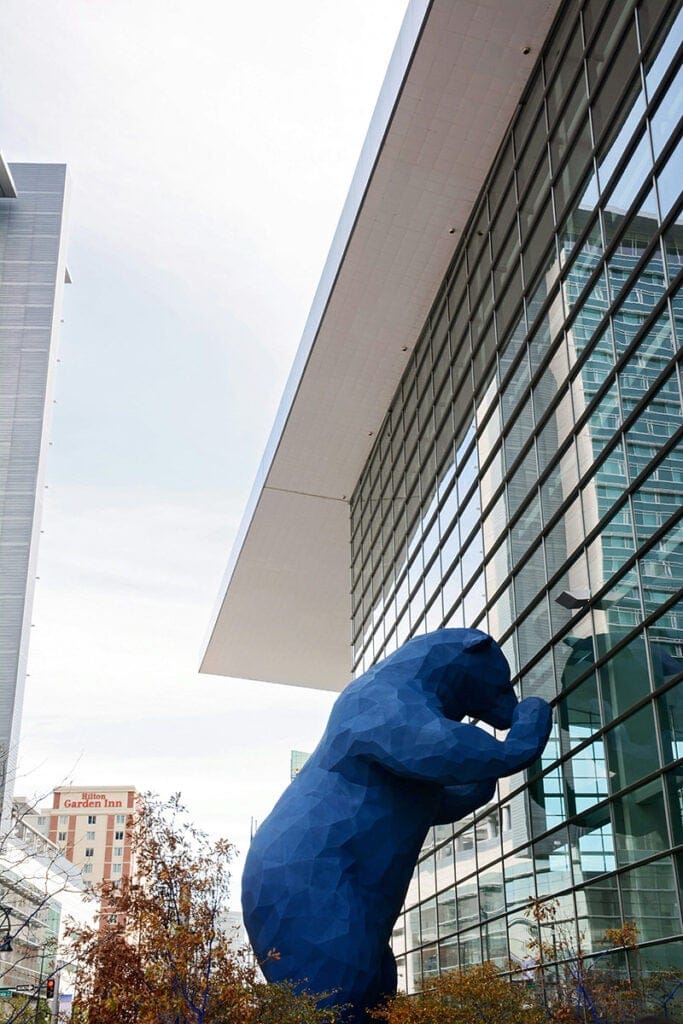 A large sculpture of a blue bear looking in the window at the Colorado Convention Center in Denver, CO.