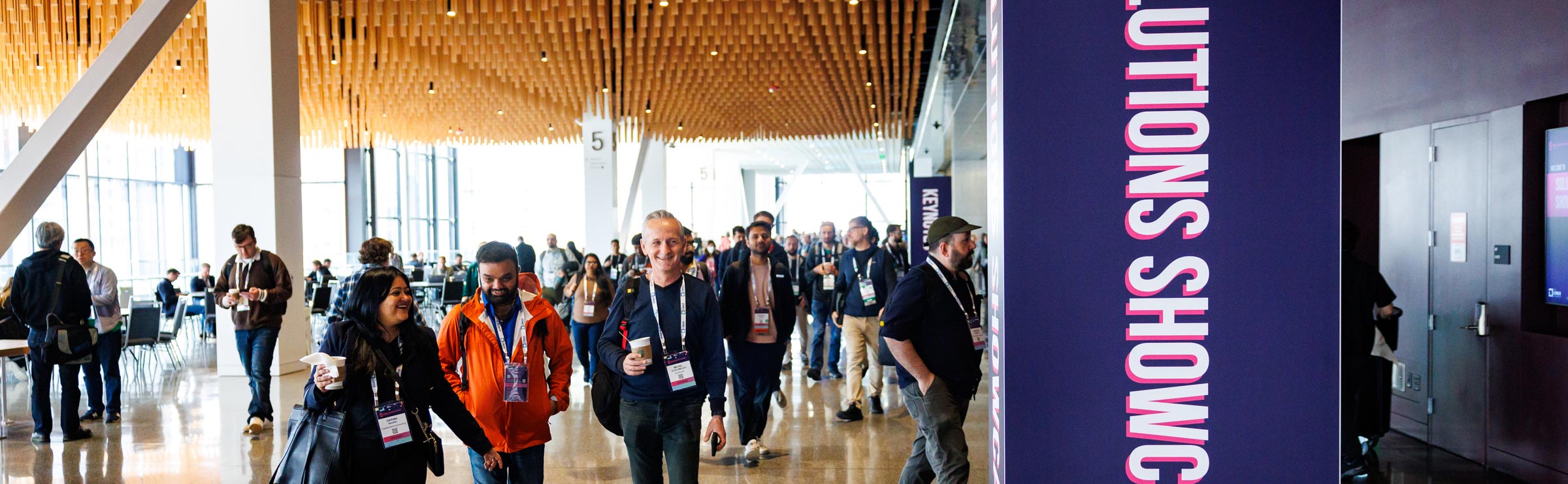 Event attendees smiling and walking through a hallway.