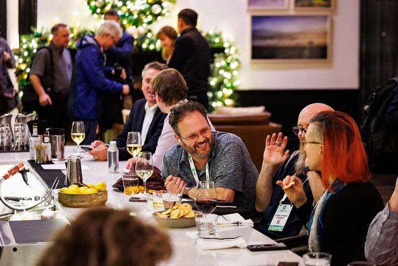 Event attendees gathered at a table enjoying snacks and beverages.