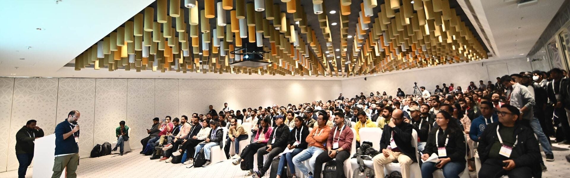 Attendees seated in a conference room with decorative walls and ceiling.