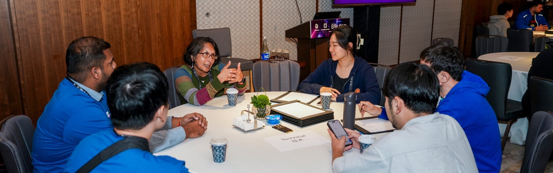 A group of people talking around a round table.