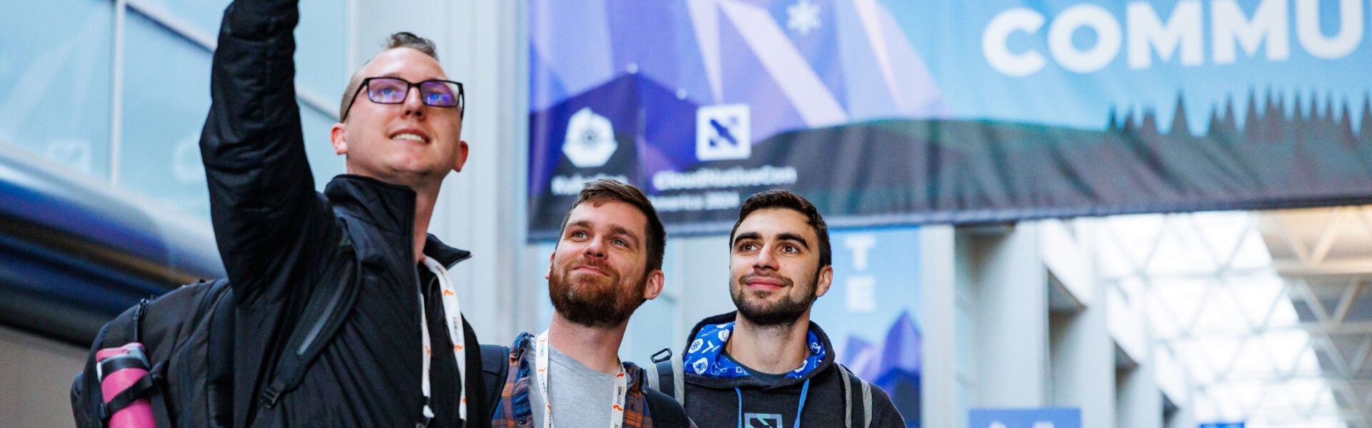 Three attendees taking a selfie in front of a conference venue.