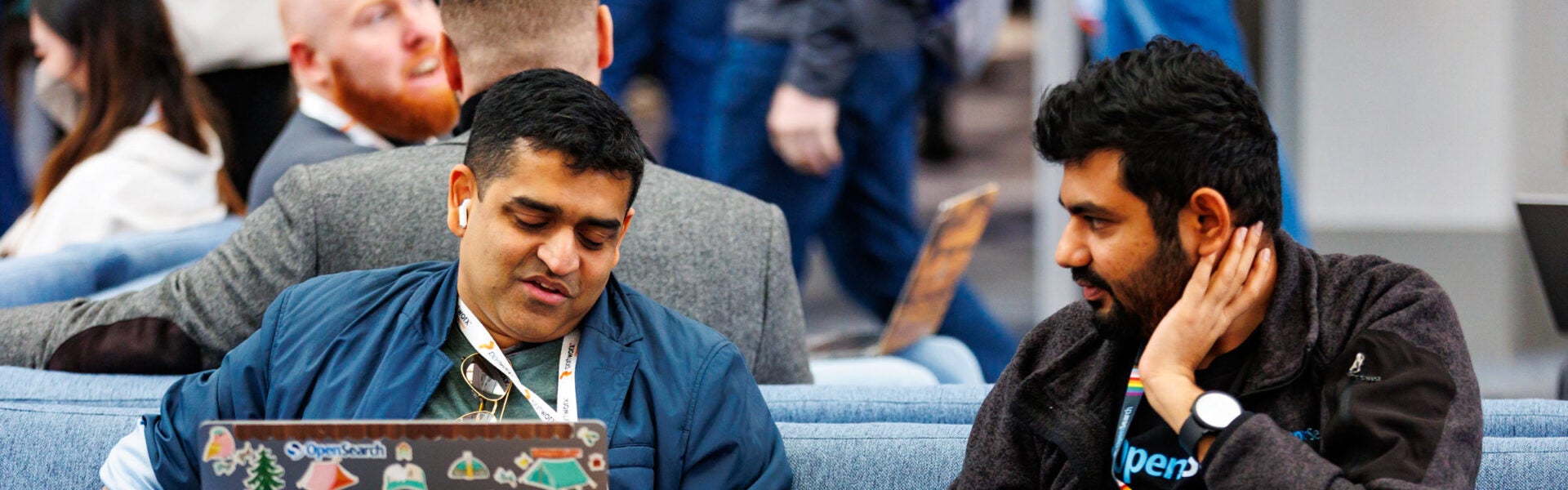 Two men talking to each other and looking at a laptop.