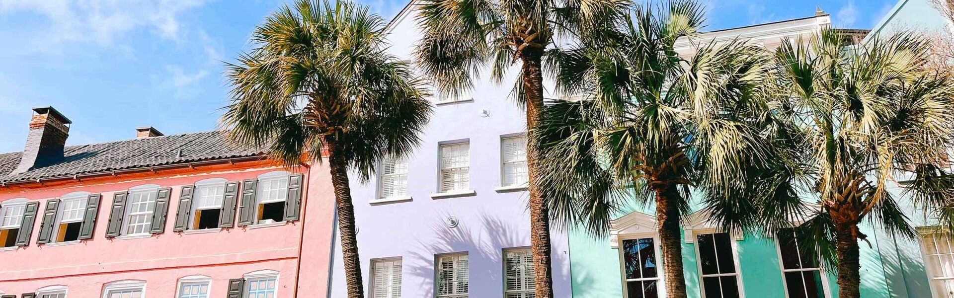 Colorful buildings in a row with palm trees in front of them.