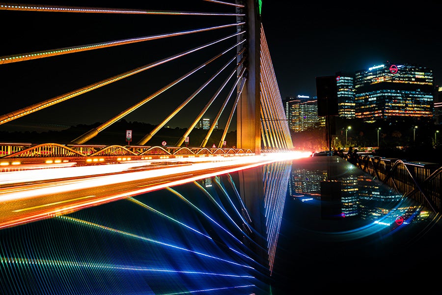 A cable bridge with the city of Hyderabad behind it in the evening. 