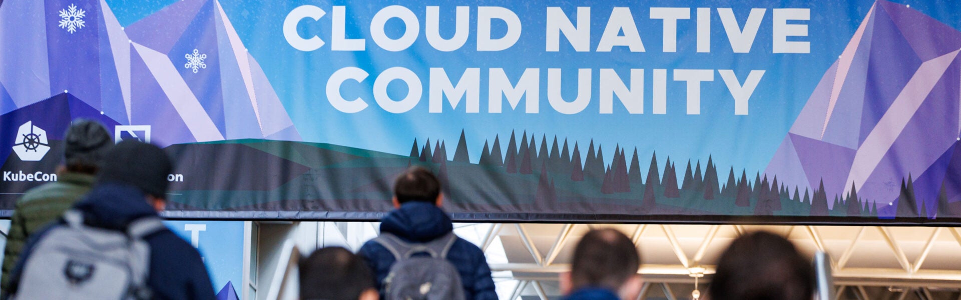 Attendees walking towards a banner that says "Cloud Native Community"