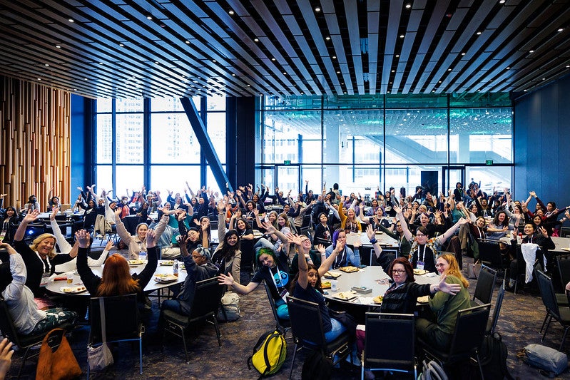 A room full of people at round tables.