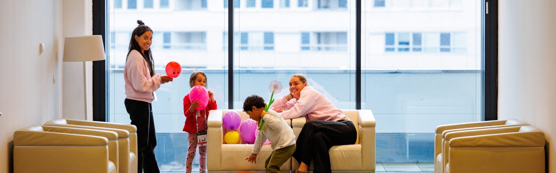 Two young children & 2 women playing with balloons.