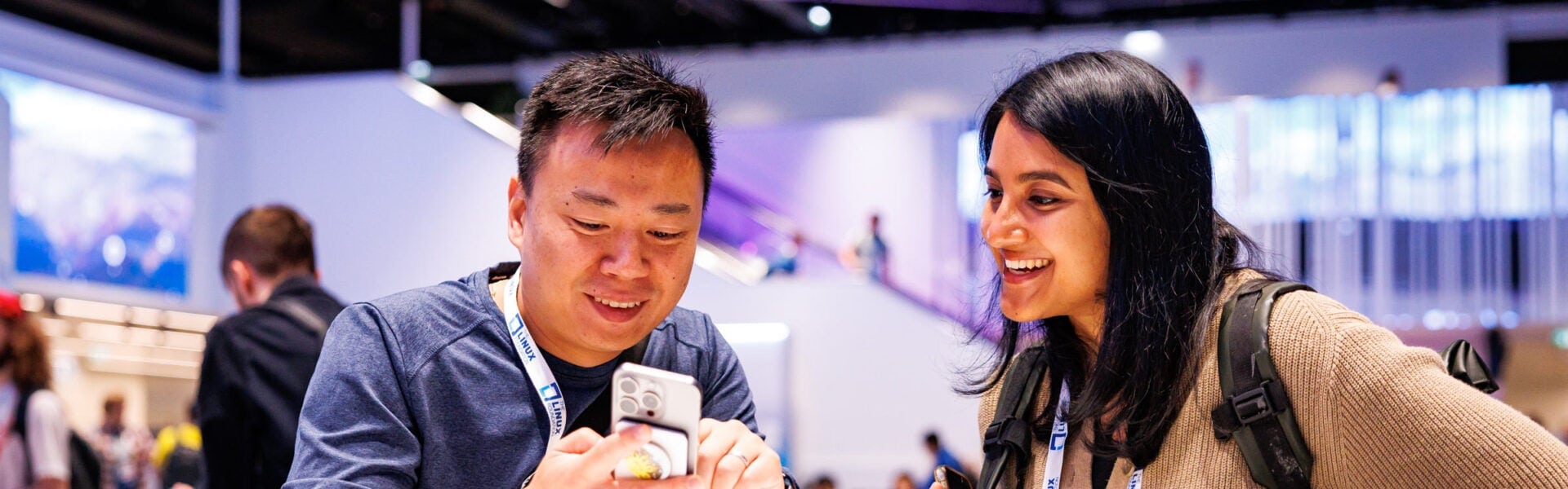 Two attendees smiling and looking at a phone.