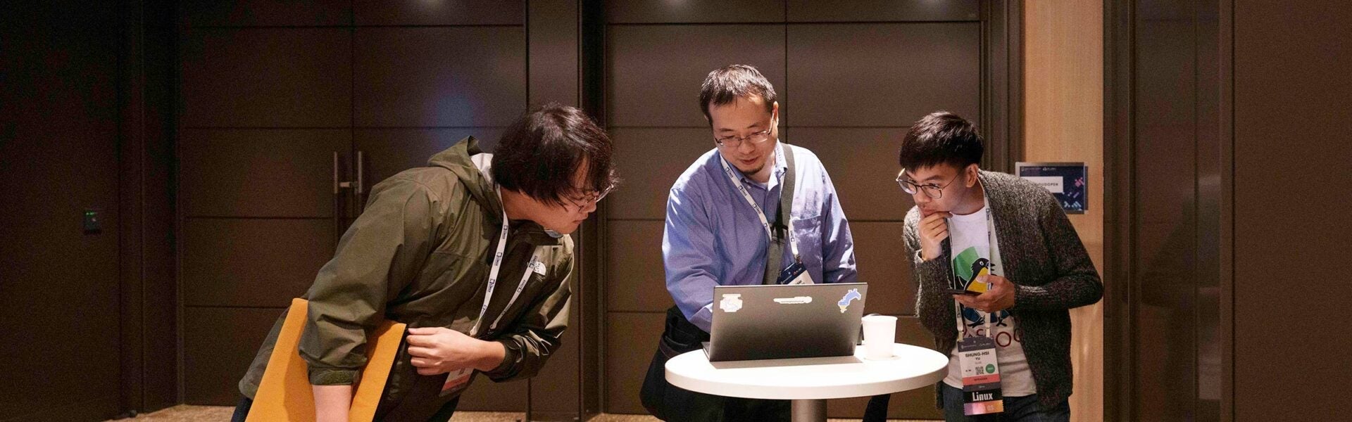 Three men looking at a laptop together.