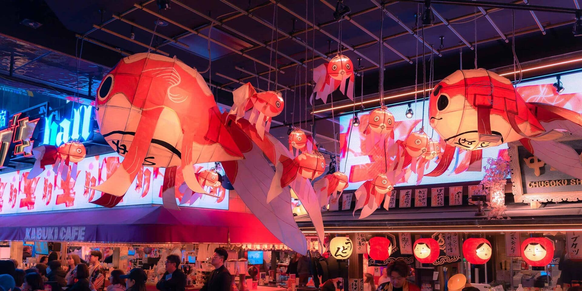 Bright red and orange fish art hanging from a ceiling.