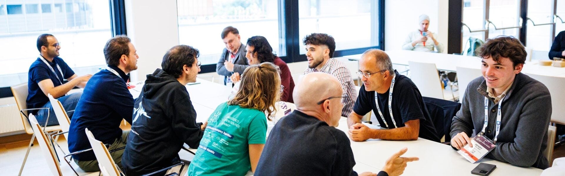 Attendees sitting at a long table, each talking to the person across from them.