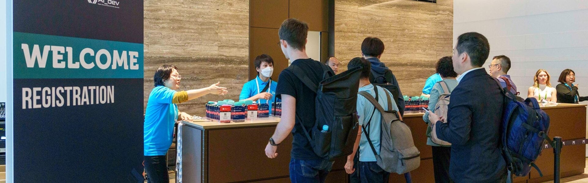 Attendees getting their registration badges near a sign that says "Welcome: Registration."