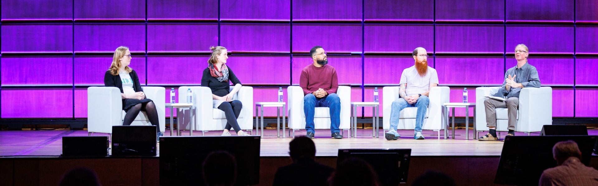 3 men and 2 women seated on stage in a speaker panel