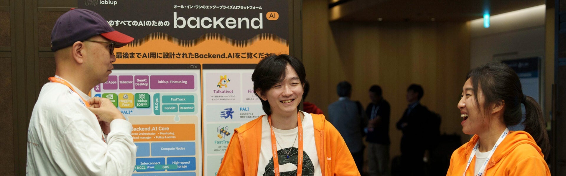 Three people standing in front of a large sign smiling and laughing