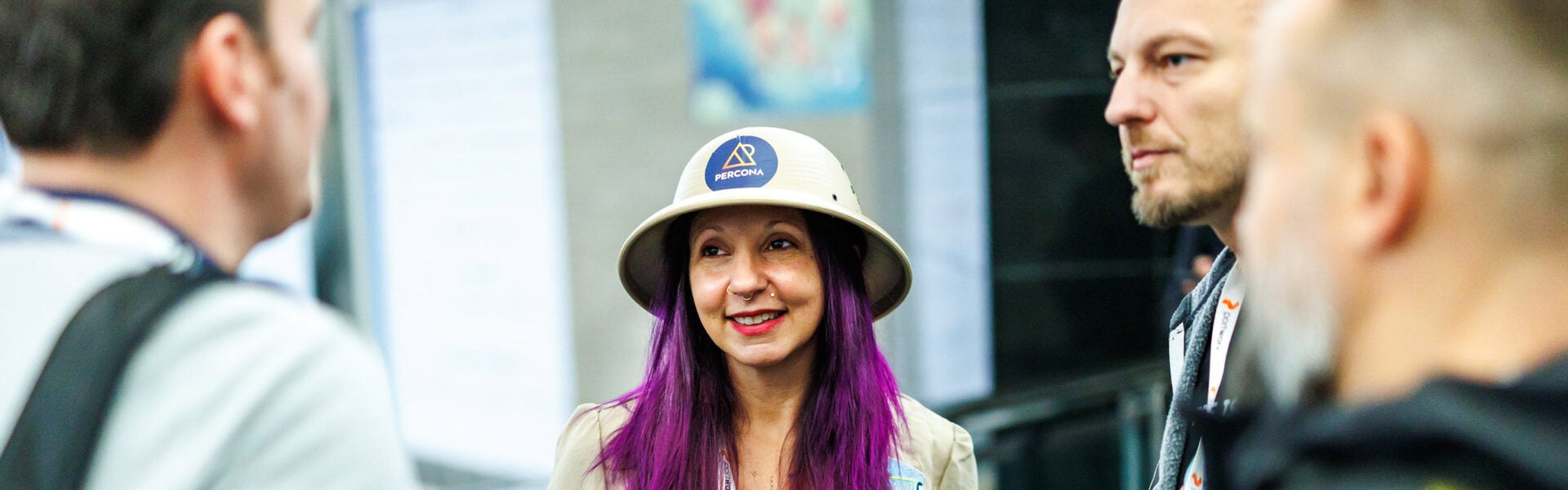 A woman with purple hat and wearing a safari hat smiling with 3 other event attendees around her.