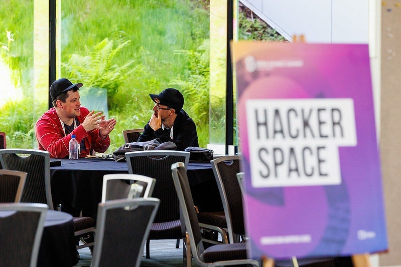 Two attendees talking behind a sign that reads "Hacker Space".