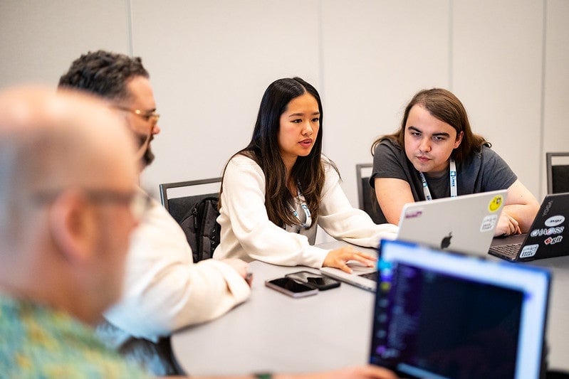 Four attendees sitting at a table looking at laptops.