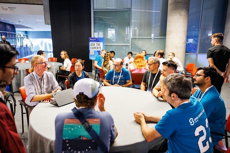 Groups of people sit at round tables talking.