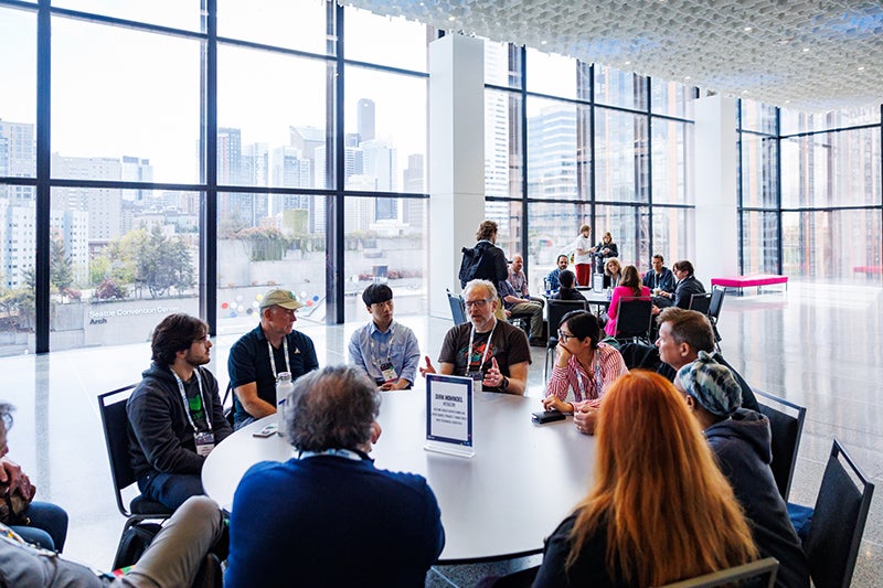 A group of people talking around a round table at an event.