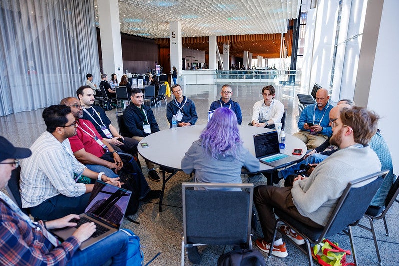 A group of people talking around a round table at an event.