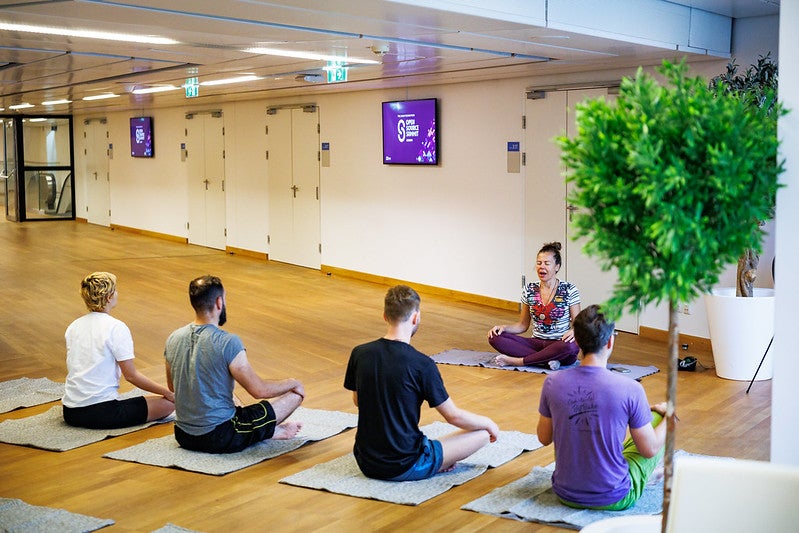 Five people sit on yoga mats doing yoga poses.