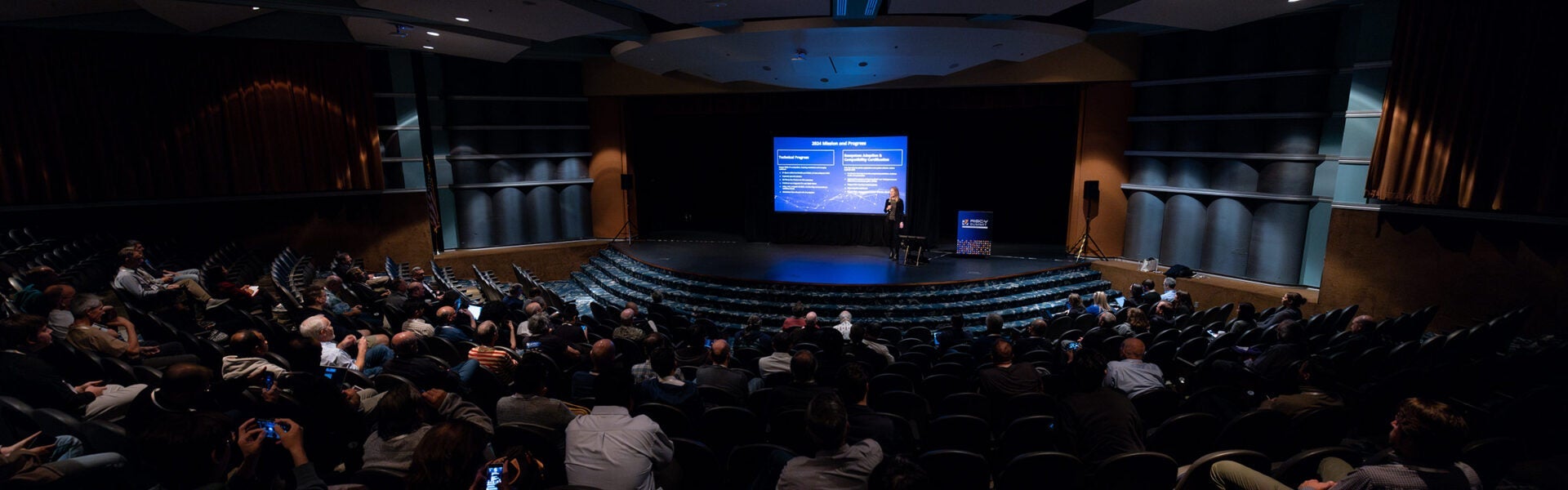 A keynote speaker on stage in an auditorium.