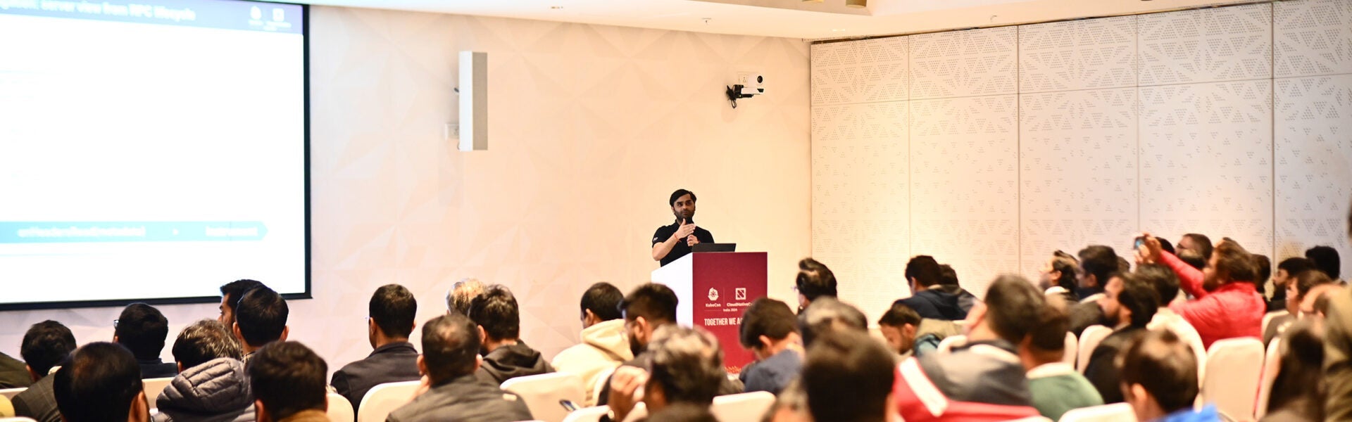 A speaker at a podium in front of a room full of people.